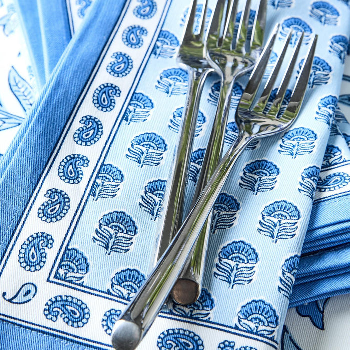 Set of four blue and white cotton cloth napkins featuring a Chinoiserie block print pattern with two silver forks.