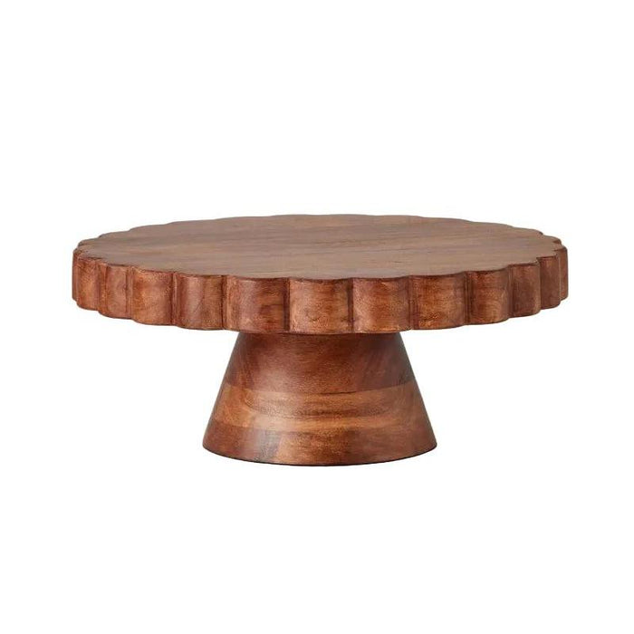 Round scalloped cake stand crafted from rich, natural acacia wood with a sturdy pedestal base and unique grain patterns.