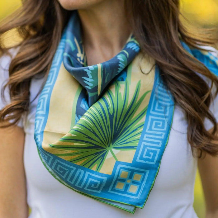 Ocmulgee Alligator silk twill scarf featuring a blue and gold palmetto design with a Greek key border worn around the neck.