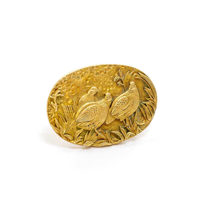 Oval brass scarf ring featuring a detailed, handcrafted relief of three quail birds in a natural landscape.