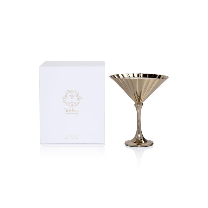 Gold martini glass-shaped scented candle in a metallic fluted vessel next to its white Vendome branded gift box.