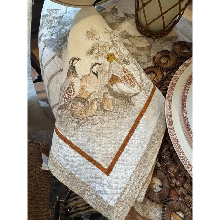 Cream-colored Italian linen napkin featuring an intricate gamebird print with a rustic brown border.