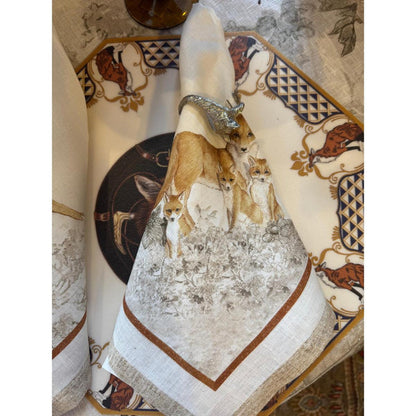 Cream-colored Italian linen napkin featuring an intricate fox print, held by a silver-toned metal animal napkin ring.
