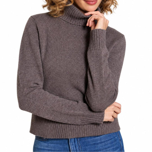 Woman wearing a cozy, brown 100% merino wool Eden fold-over turtleneck sweater with ribbed cuffs and hem.