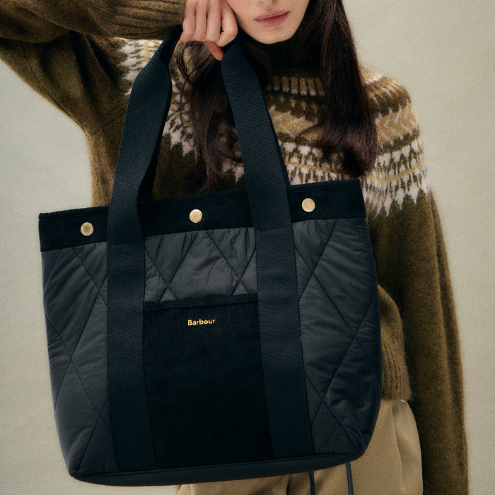Black Barbour Healy quilted tote bag with webbed handles, cord trim, and gold snap button details.