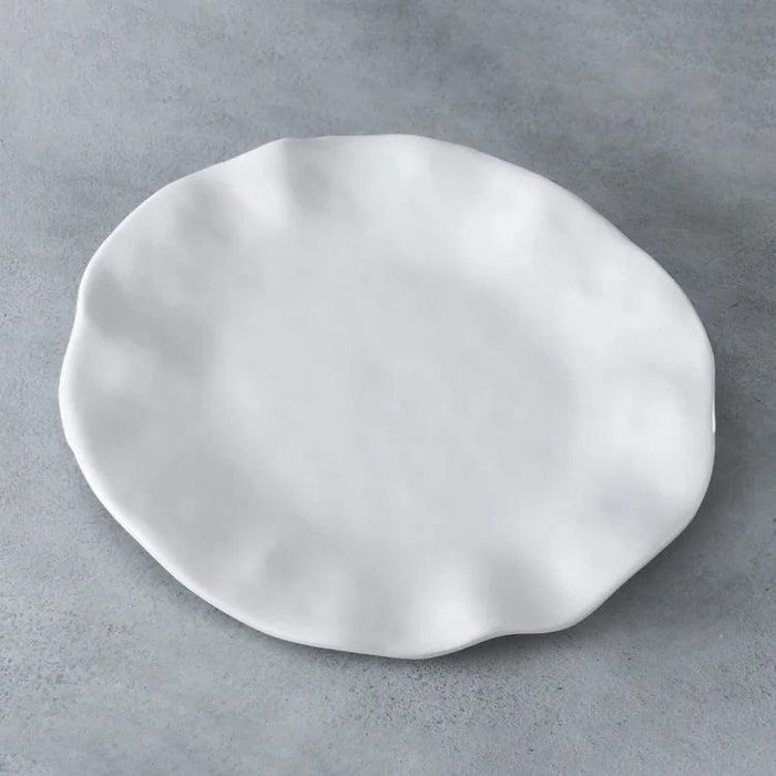 Beatriz Ball Vida Havana 11-inch white melamine dinner plate with a wavy, organic edge on a grey background.