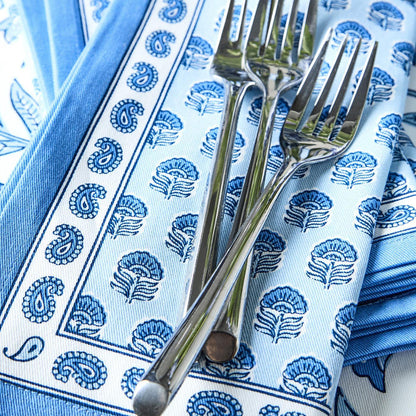 Set of four blue and white cotton cloth napkins featuring a Chinoiserie block print pattern with two silver forks.