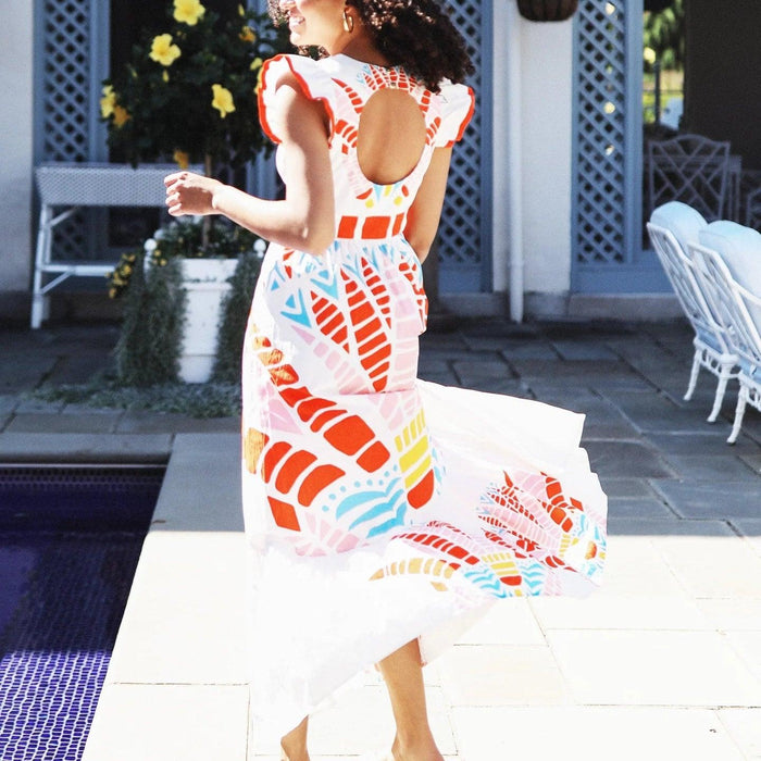 CK Bradley Henning cotton dress with flutter sleeves, open back, and colorful abstract print on a tiered white skirt.