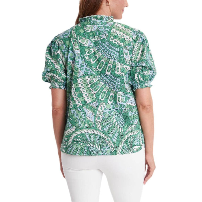 CK Bradley Cayman top in green patterned cotton with a ruffled collar and puff sleeves, paired with white pants.