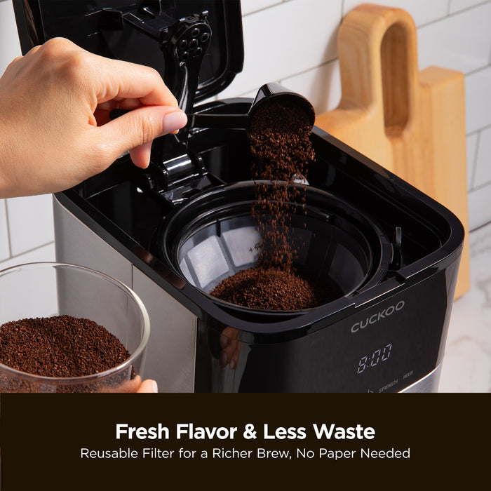 Scooping coffee grounds into a Cuckoo coffee maker. Text: Fresh Flavor & Less Waste, Reusable Filter for a Richer Brew. (CCM-BD011B)