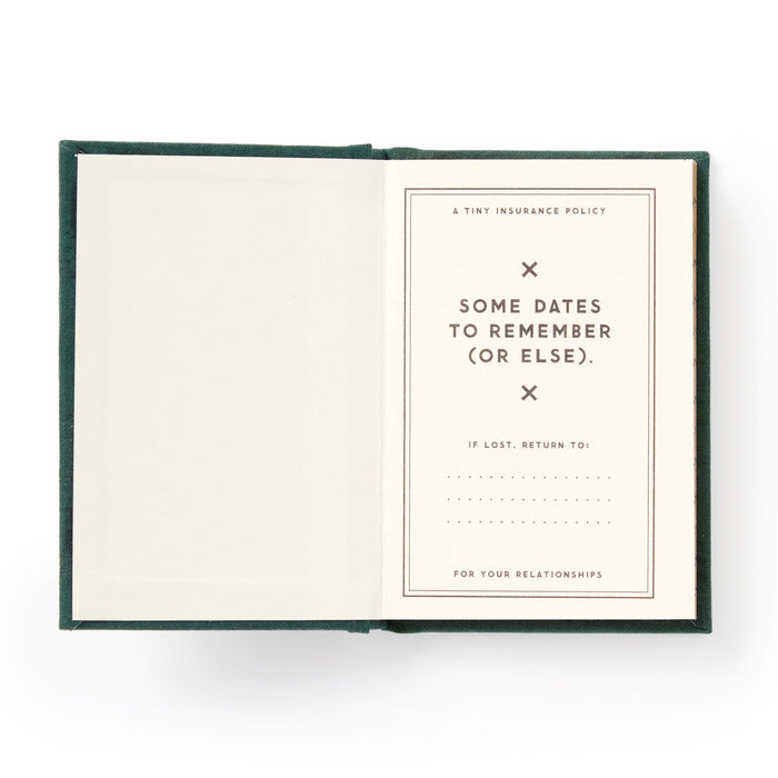 A hard-bound Brass Monkey Dates People Get Mad If I Forget Tiny Diary lies open with gilded pages: one blank, the other titled A Tiny Insurance Policy—Some Dates to Remember (Or Else), plus a spot for contact info if lost.
