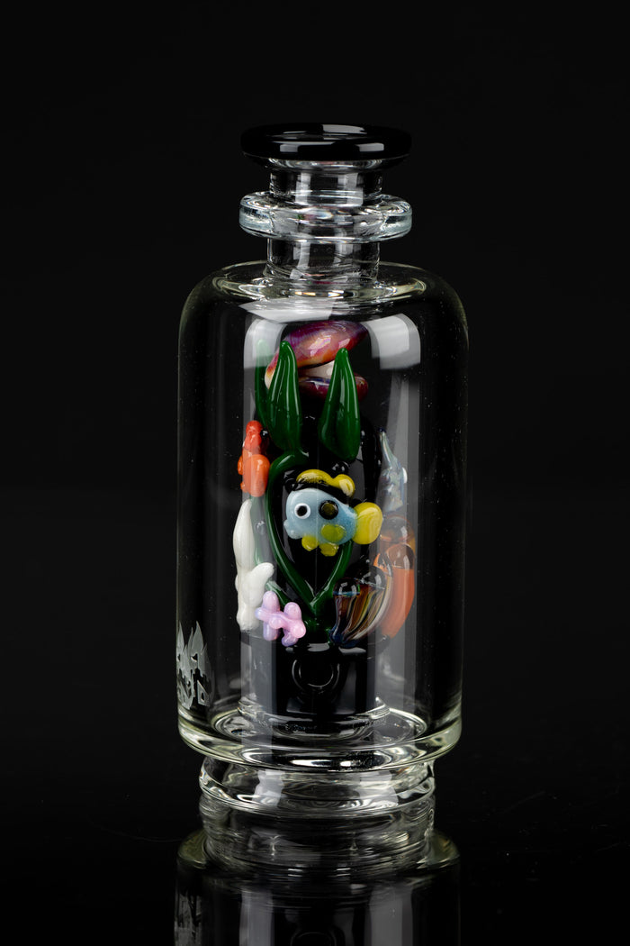 Clear glass bubbler with colorful sculpted glass flowers and foliage inside, reflecting on a glossy black surface.