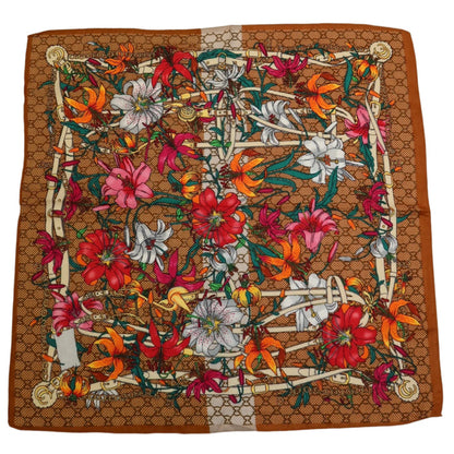 27-inch square polyester twill scarf with a brown monogram background and vibrant floral lily print in red, orange, and white.