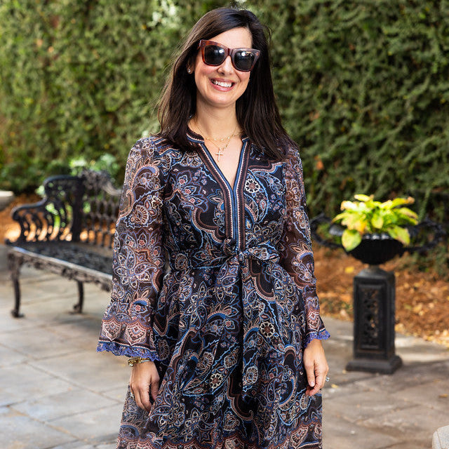 Woman wearing a Hale Bob Artemis short dress with 3/4 sleeves, a tie belt, and a blue and brown paisley print.