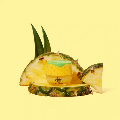 Small container with a bee logo on a pineapple slice against a yellow background