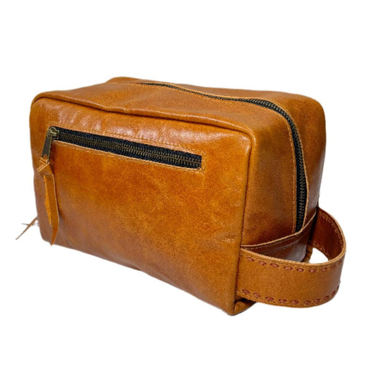 Tan premium leather shave bag with a side handle, black zipper, and hand-stitched detailing for travel organization.