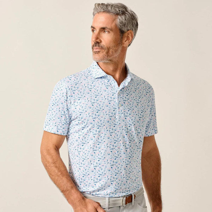 Man wearing a white Johnnie-O performance polo with a patriotic novelty print, spread collar, and three-button placket.