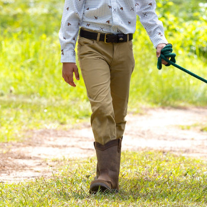 Child wearing tan performance briar pants with a tailored jean fit and brown leather belt while walking outdoors.