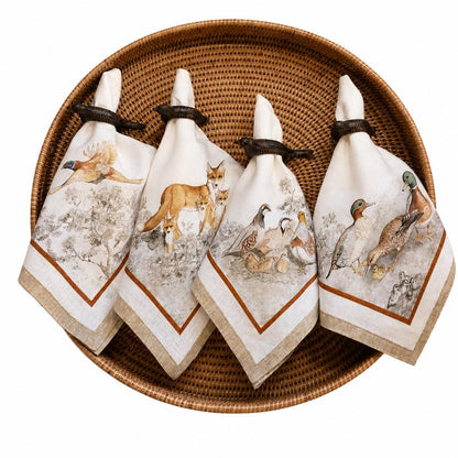 Set of four cream Italian linen napkins featuring intricate gamebird and fox illustrations in rustic napkin rings.