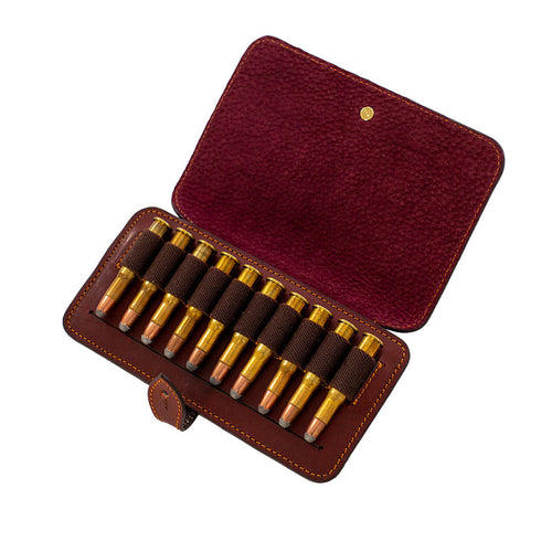 Handcrafted burgundy leather rifle cartridge wallet holding ten bullets with a secure flap and cufflink closure.