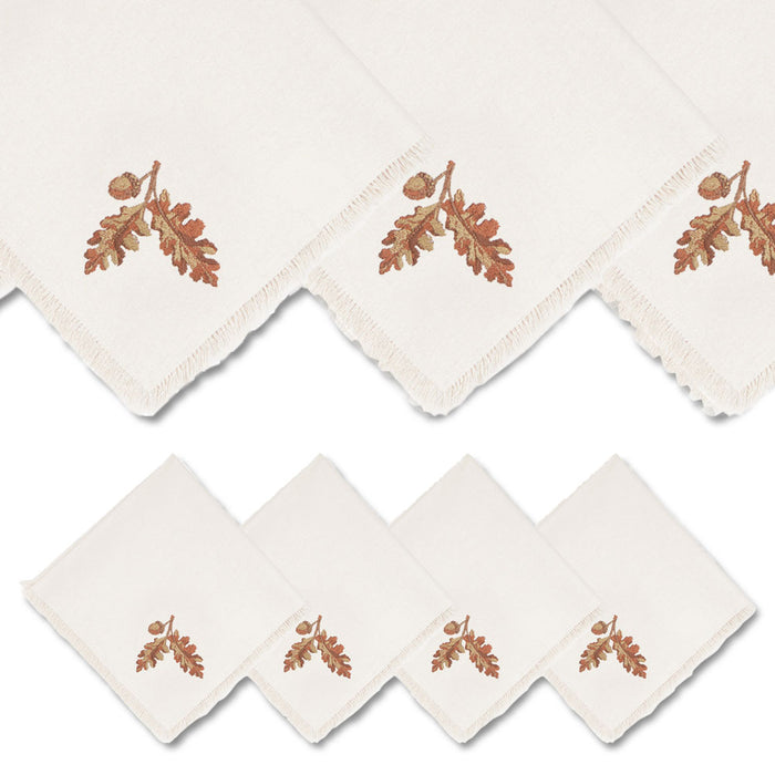 Set of four 18-inch cream linen dinner napkins featuring embroidered acorn designs and elegant fringe edges.
