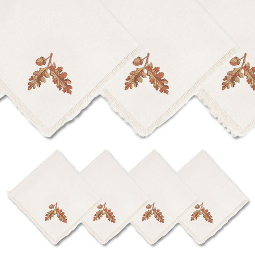Set of four 18-inch cream linen dinner napkins featuring embroidered acorn designs and elegant fringe edges.