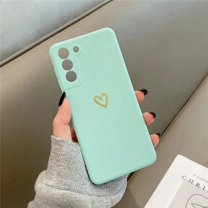 A mint green phone case with a gold heart design.