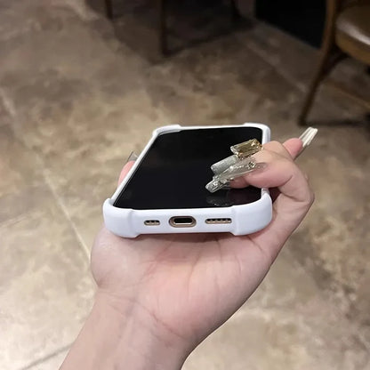 White smartphone in a protective case with long, decorative fingernails holding it.