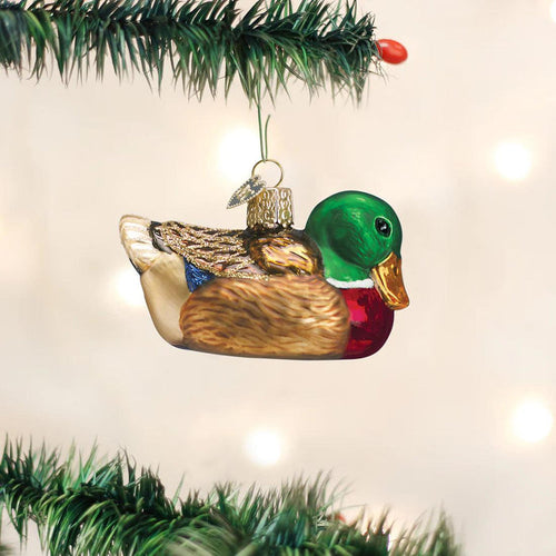 Hand-painted glass mallard duck ornament with glitter accents, hanging from a Christmas tree branch.
