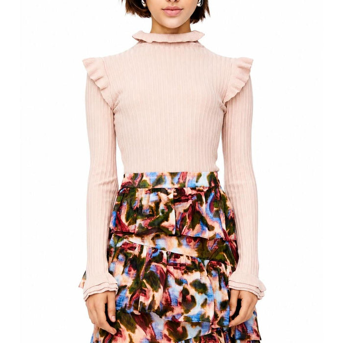 Soft blush pink ribbed turtleneck sweater with ruffled shoulders and collar, styled with a colorful tiered skirt.