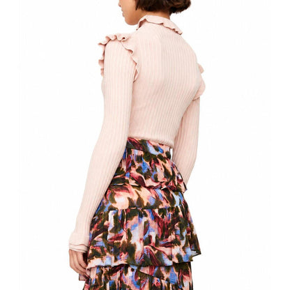 Blush pink ribbed turtleneck sweater with ruffle trim on the collar and shoulders, paired with a tiered floral skirt.