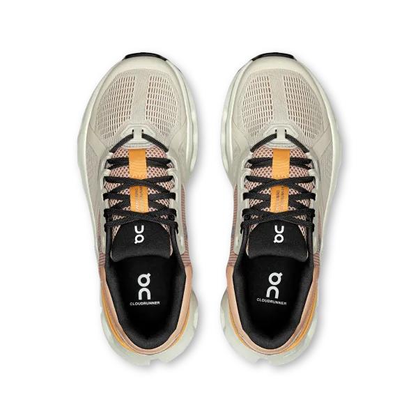 Top-down view of beige On Running Cloudrunner 2 wide women's shoes with black laces and orange tongue detailing.