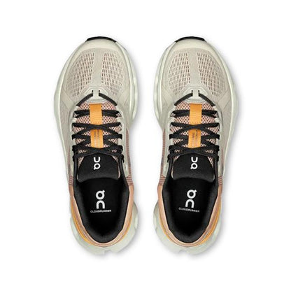 Top-down view of beige On Running Cloudrunner 2 wide women's shoes with black laces and orange tongue detailing.