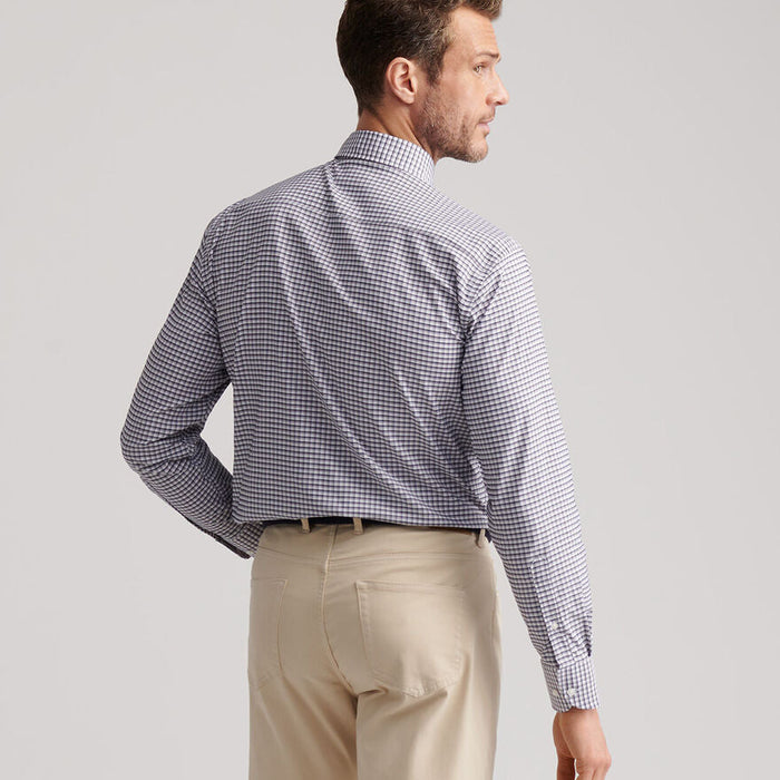 Man wearing a Peter Millar blue and white checkered performance twill long-sleeve button-down shirt with khaki pants.