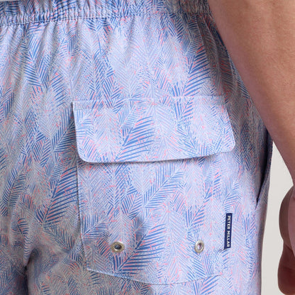 Peter Millar swim trunks in light blue with a pink palm leaf print, featuring a back pocket and elastic waistband.