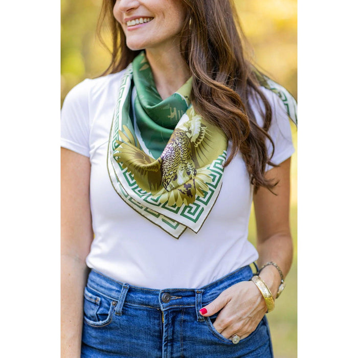 Green silk twill scarf featuring an English pointer and quail motif with a classic Greek key border, worn around the neck.