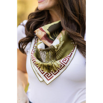 Silk twill scarf featuring an English pointer, quail, and Greek key border in navy, ochre, and cream on a woman.