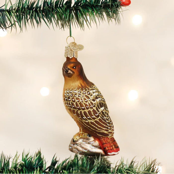Hand-painted blown glass Red-Tailed Hawk ornament with glittered feather details, hanging on a Christmas tree.