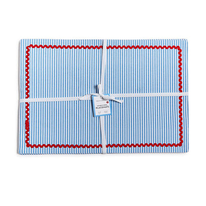 Set of 4 blue and white striped cotton placemats with red rickrack trim, tied with a white ribbon.