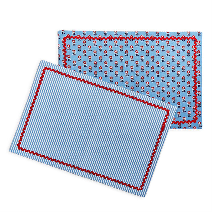 Reversible cotton placemats with blue floral print and blue striped pattern, finished with a red scalloped trim.