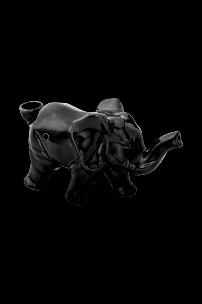 A striking side view of the Roast & Toast Lucky Elephant Ceramic Pipe, showcasing its detailed sculpted form against a dark backdrop.