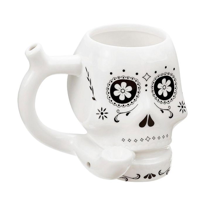 Three-quarter view of the Roast & Toast "Sugar Skull" Ceramic Pipe Mug showing its white skull shape, black floral eye designs, side handle stem, and front bowl.
