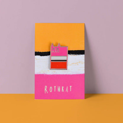 Enamel pin on a card with 'ROTHKAT' branding against a pink and orange background