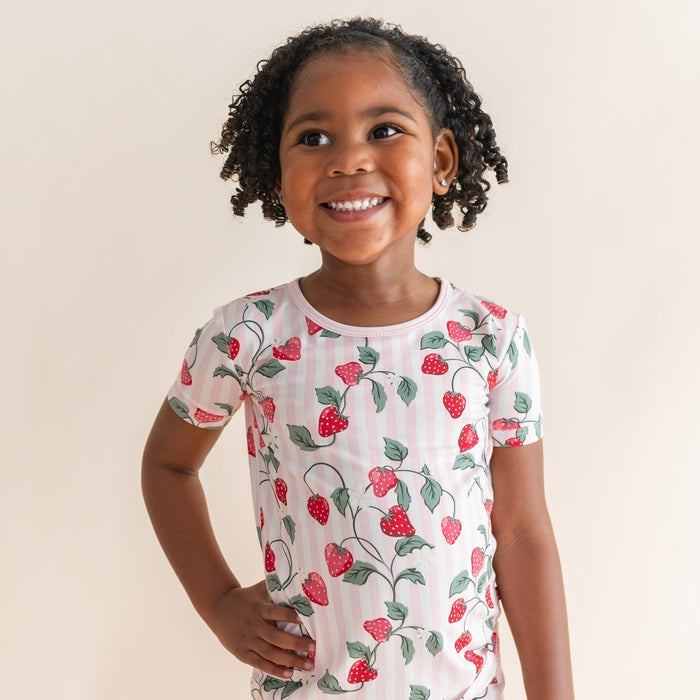 Close up of the shirt of the Short Sleeve Pajamas in Strawberry Fields shown on a smiling girl