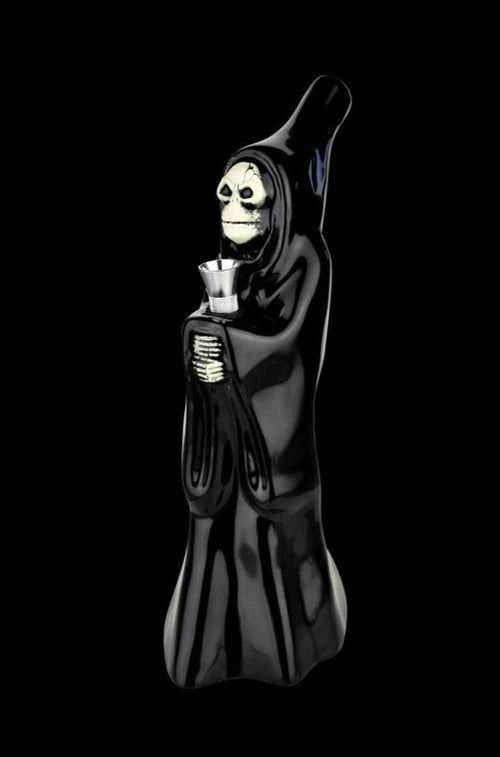 Three-quarter view of the Ceramic Bong - Skeleton Cupbearer, a glossy black hooded skeleton figure holding a metal cup against a black background