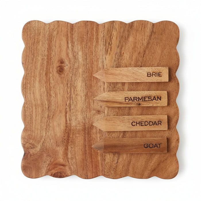 Square acacia wood cheese board with scalloped edges and four labeled wooden cheese markers.