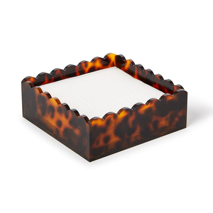 Square acrylic cocktail napkin holder with a brown tortoise print and decorative scalloped edges.
