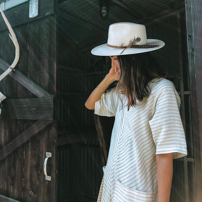 Woman wearing a white Japanese Toyo straw Valencia hat with a leather strap and feather accent.