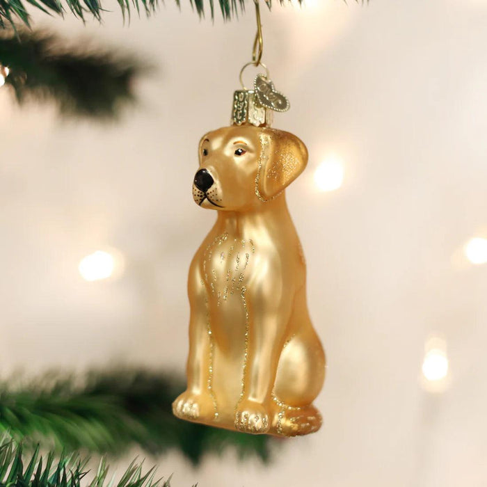 Hand-painted yellow Labrador blown glass ornament with glitter accents, hanging on a Christmas tree.